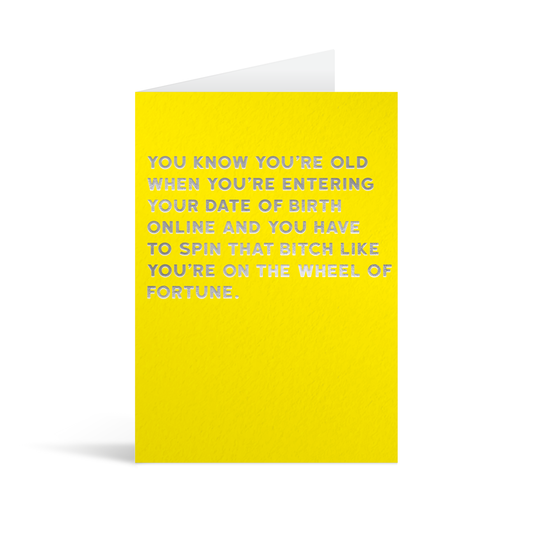 Yellow card with silver foiled text that reads "You know you're old when you're entering yout date of birth online and you have to spin that bitch like you're on the wheel of fortune."