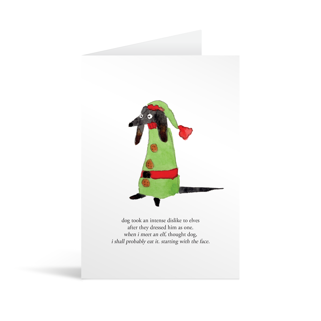 Card featuring a charming characterful somewhat bemused dog dressed as an elf with text underneath describing how the dog hates elves and will eat one when he meets it, starting with the face