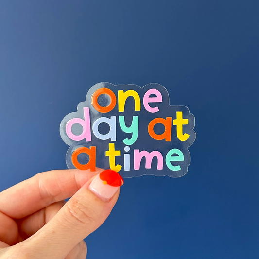 Colourful sticker reading "One day at a time"