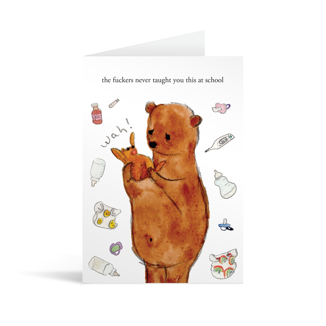White rectangular card with a painting of a big brown bear holding a crying baby bear underneath the typed words "the fuckers never taught you this at school". Brown envelope in the background.