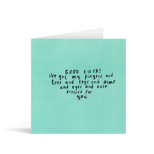 A textured turquoise card with the handwritten words "Good Luck! I've got my fingers and toes and legs and arms and eyes and nose crossed for you."