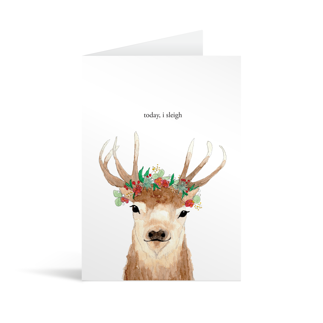 Beautiful card featuring a watercolour illustration of a dear, antlers adorned with woodland flowers and berries, underneath the words "today, I sleigh"