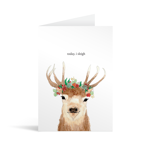 Beautiful card featuring a watercolour illustration of a dear, antlers adorned with woodland flowers and berries, underneath the words "today, I sleigh"