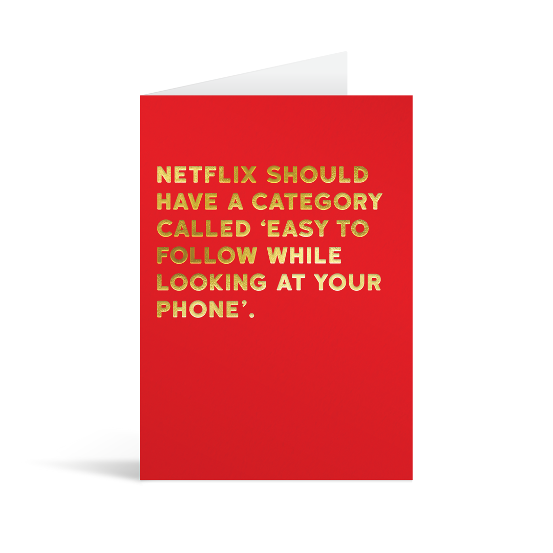 Red rectangular card with gold foiled text saying: "Netflix should have a category called 'easy to follow while looking at your phone."