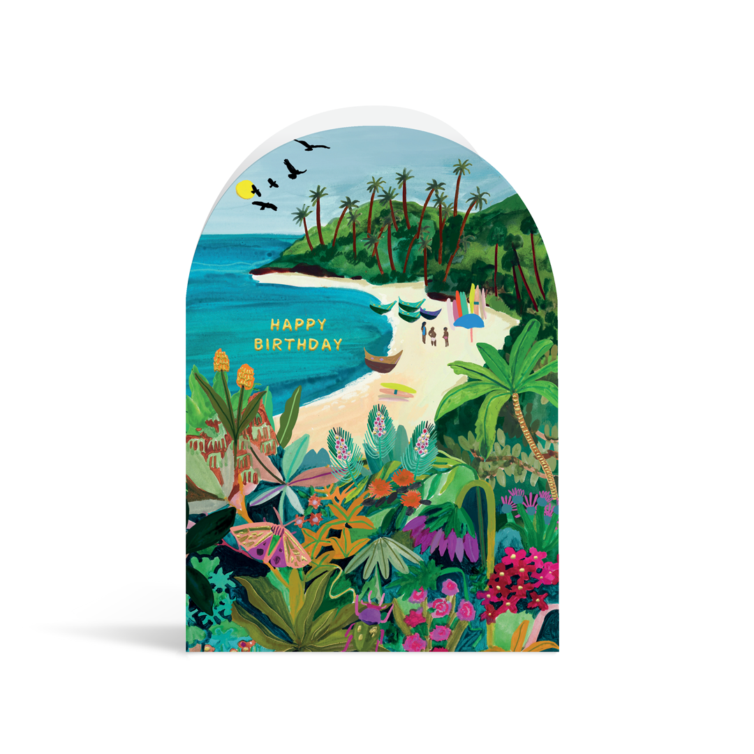 A bright, arch-shaped card painted in vibrant turquoises, greens and yellows. The scene depicts a tropical palm beach with a group of people and boats, a butterfly in the foreground and gold foiled text reading Happy Birthday