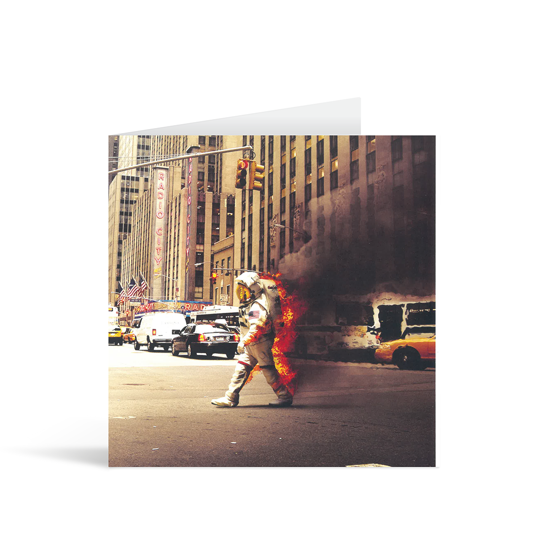 A square photographic card with a cool contemporary digitally enhanced image of a spaceman on fire walking through the streets of New york.