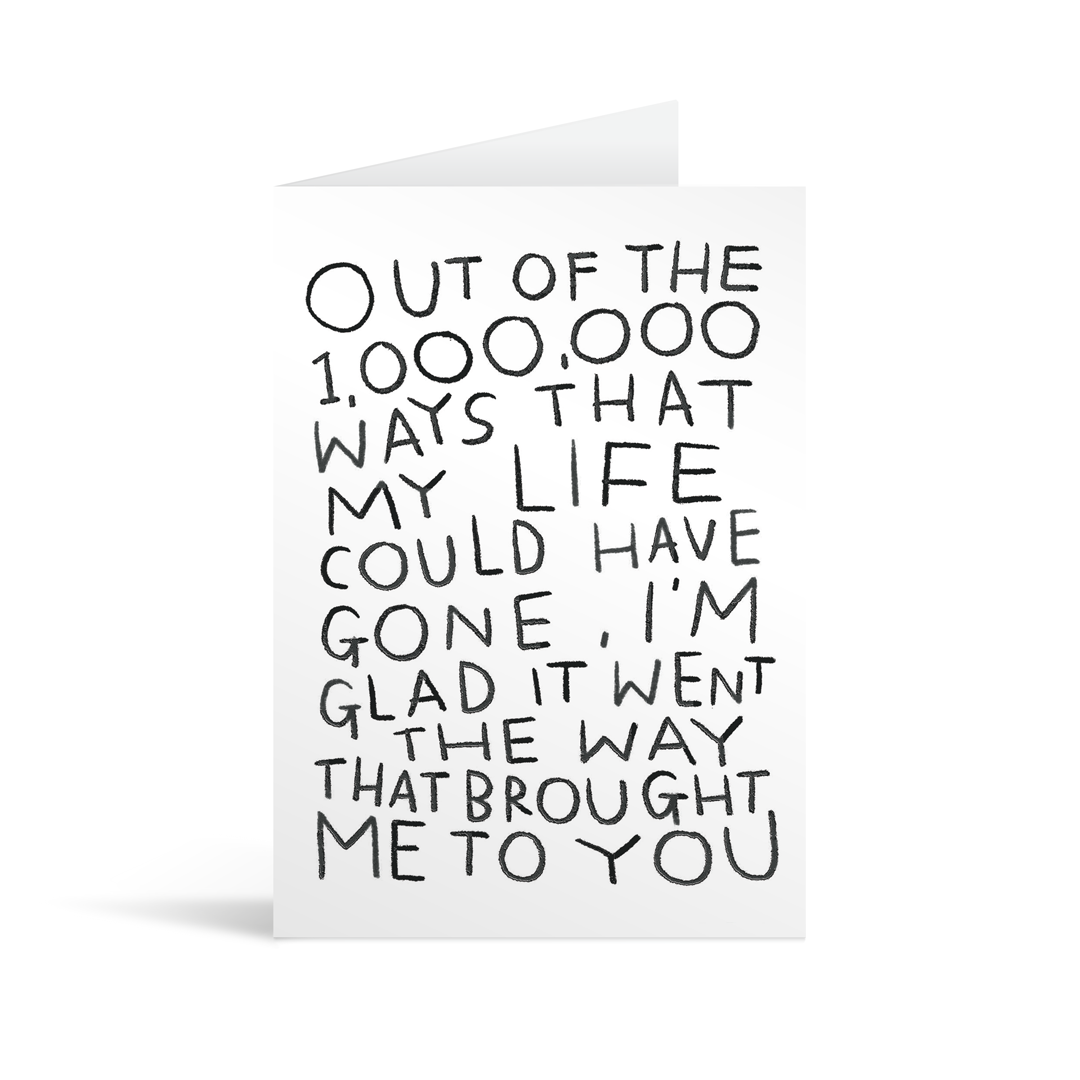 A romantic black and white card with fun quirky writing on it that reads "Out of the 1000000 ways that my life could have gone, I'm glad it went the way that brought me to you"