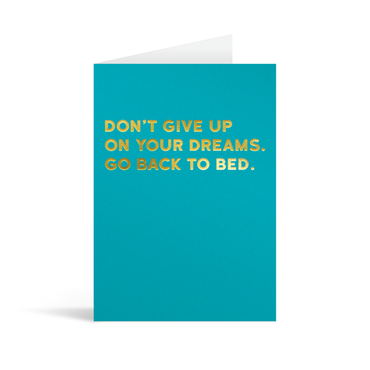 Bright blue card with gold foiled text saying: "Don't give up on your dreams. Go back to bed."