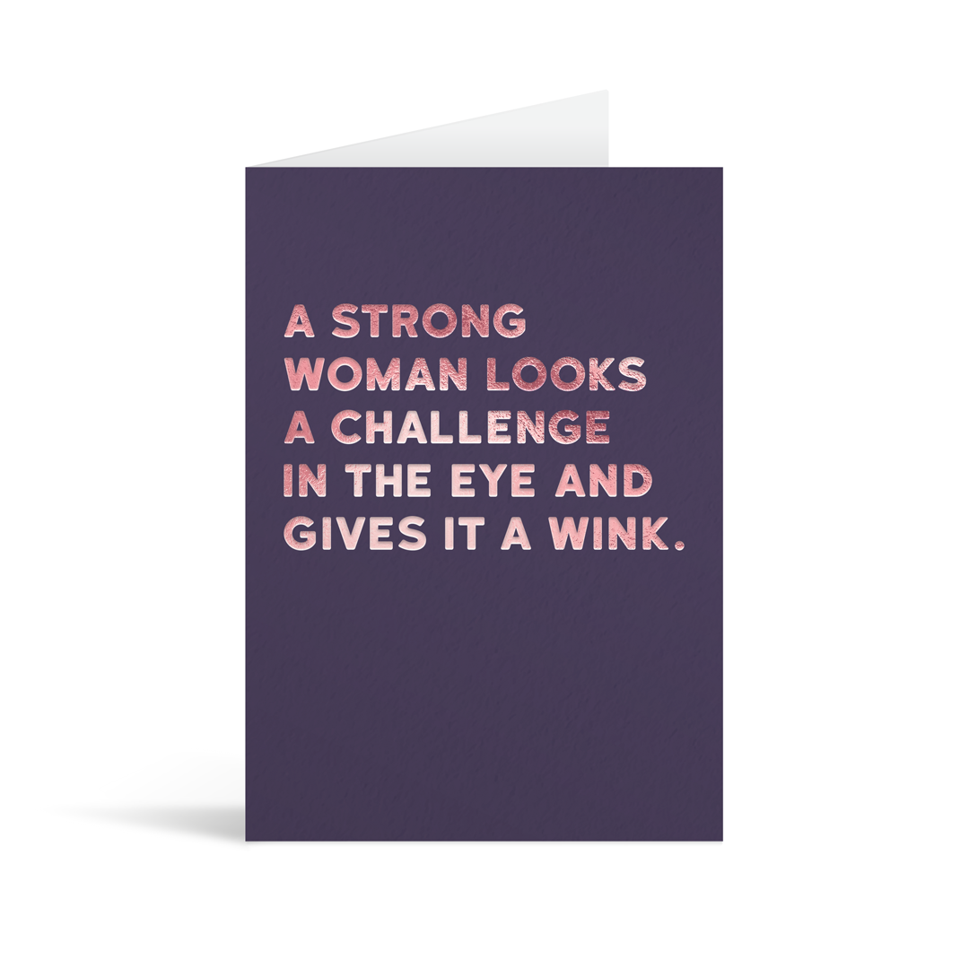 Violet rectangular card with pink foiled text saying: " A stong woman looks a challenge in the eye and gives it a wink." 