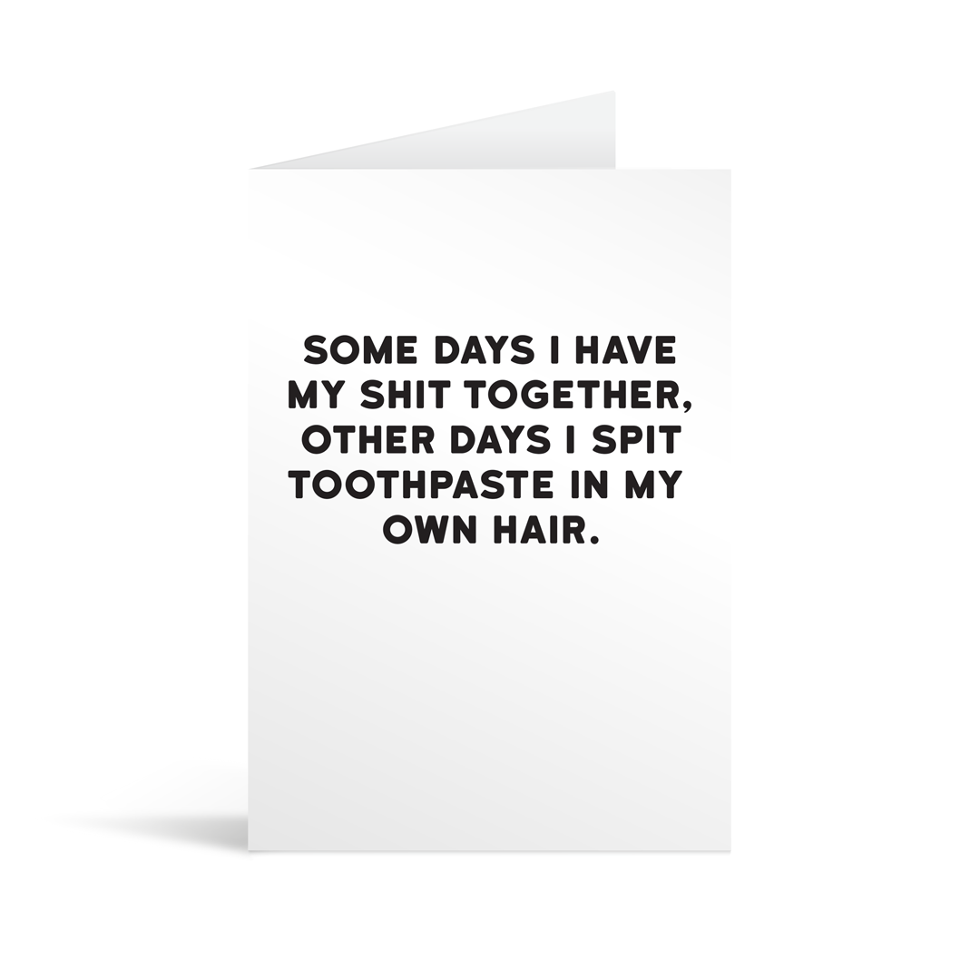 White rectangular card with funny black text saying: "Some days I have my shit together, other days I spit toothpaste in my own hair."