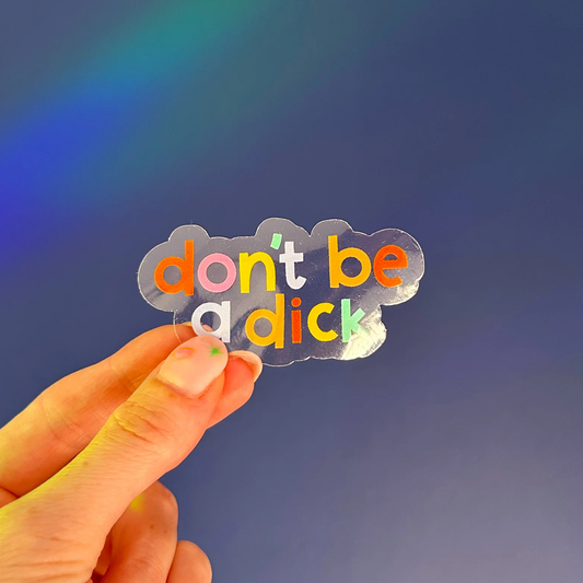 Transparent gloss vinyl sticker with multicoloured text saying "don't be a dick" on a navy blue background