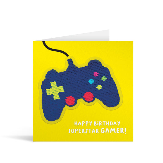 Yellow square greetings card with colourful shiny sequin games console reversible patch and fun, free-flowing text that reads "Happy Birthday Superstar Gamer!"