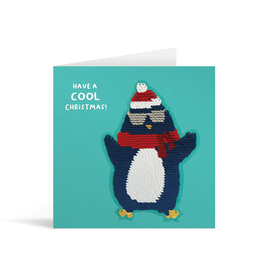 Turquoise square greetings card with reversible sequin penguin patch and fun, free-flowing text that reads "Have a COOL Christmas!"