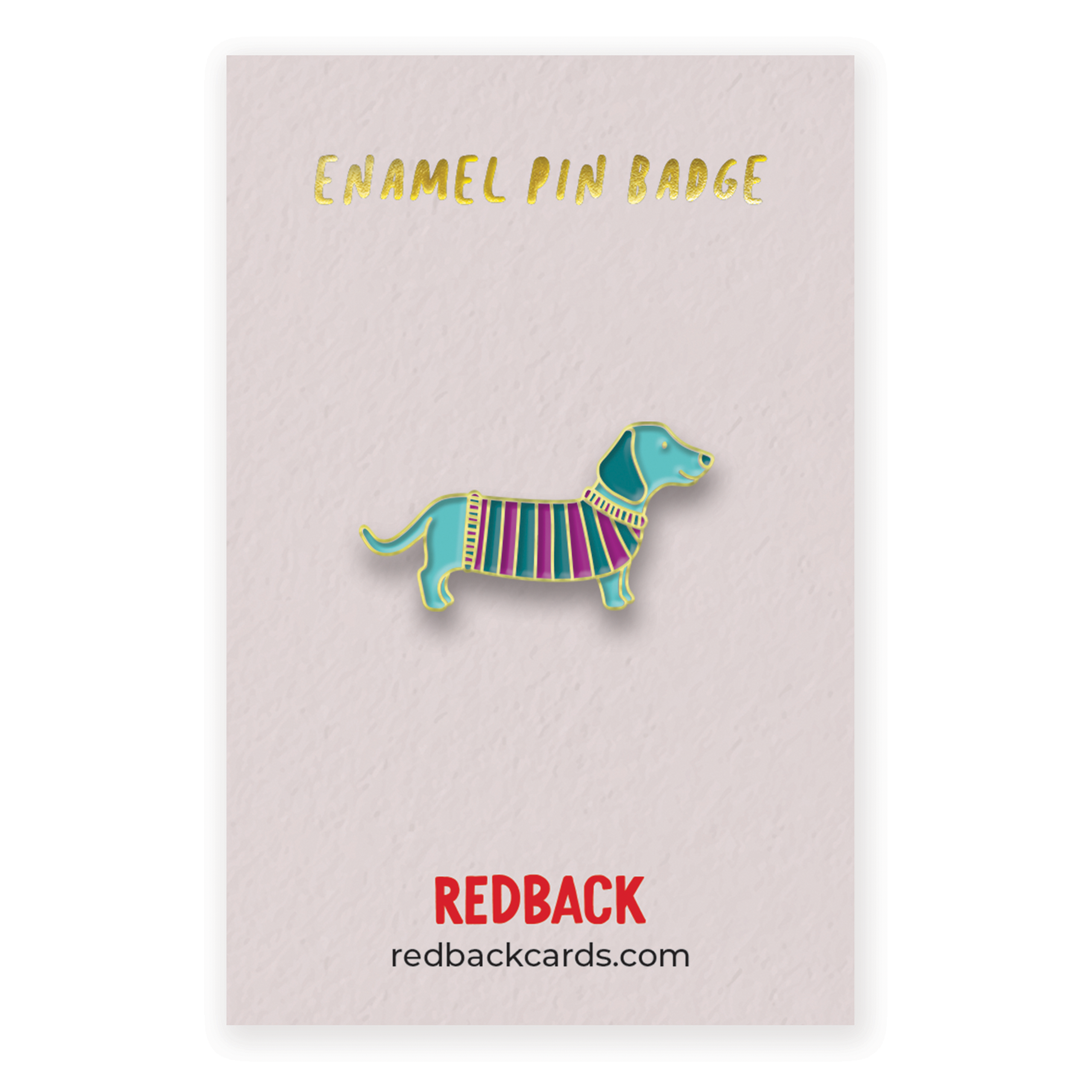 A cute blue sausage dog enamel pin in a dark blue and purple striped jumper with gold detailing.