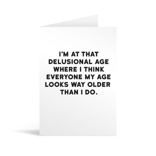 White rectangular card with black text saying: "I'm at that delusional age where I think everyone my age looks way older than I do."