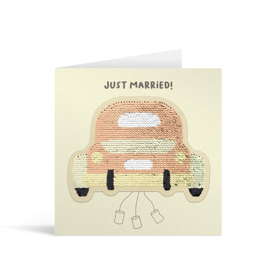 Cream square greetings card with pearlescent shiny sequin car patch, complete with traditional tin cans trailing behind and fun, free-flowing text that reads "Just Married!"