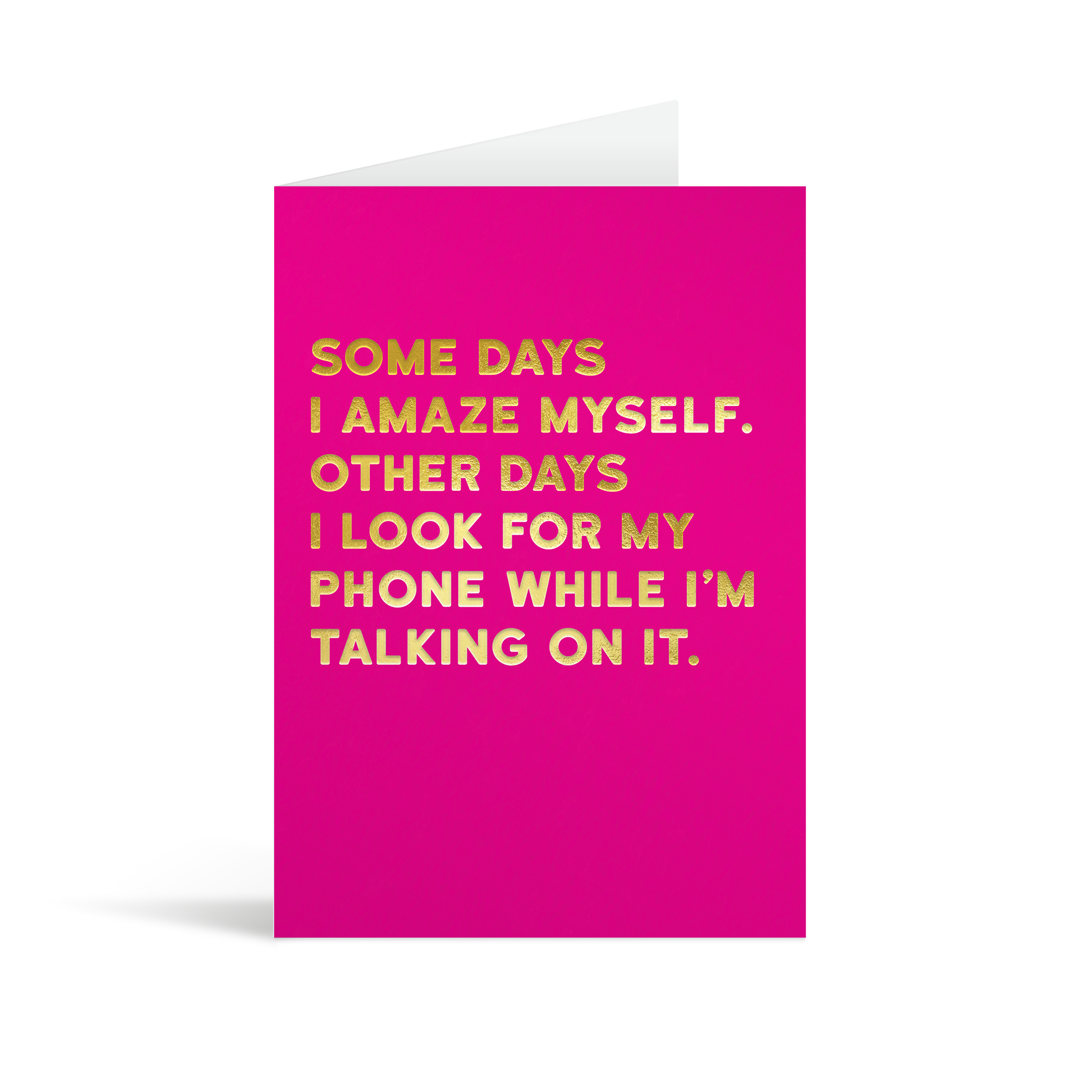 Bright pink rectangular card with gold foiled text saying: "Some days I amaze myself. Other days I look for my phone while I'm talking on it."