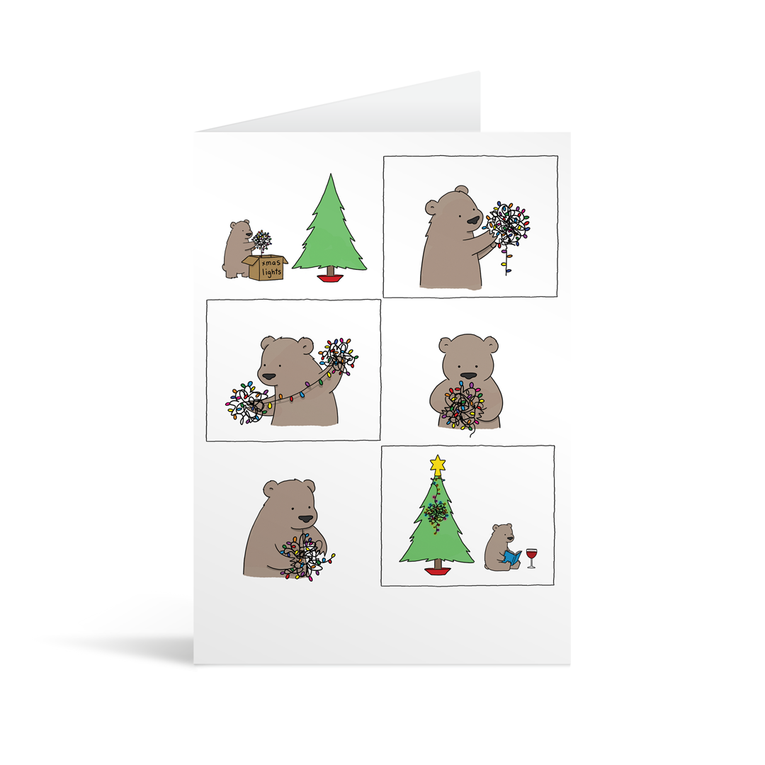 A comic style illustrated card showing a cute brown bear struggling with christmas lights, before eventually giving up, sticking them on the tree in a tangled bundle, sitting down and drinking a glass of wine whilst reading a book with his back to the tree