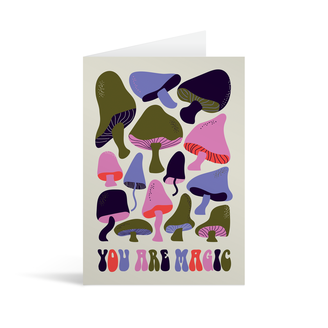 Grey rectangular card with many stylised mushrooms in psychedelic colour with the words "You are magic" printed at the bottom. Brown envelope in background.