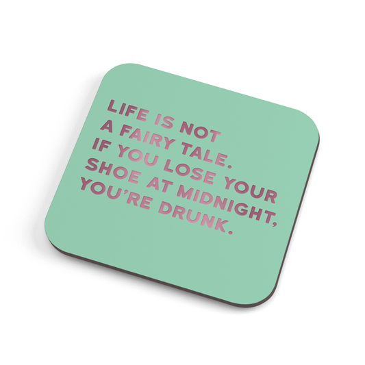 A funny green coaster with lavender foiled text saying "Life is not a fairy tale. If you lose your shoe at midnight, you're drunk."