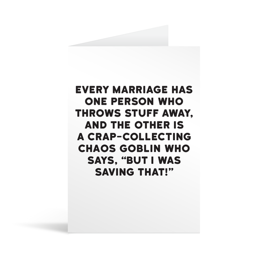 White rectangular card with black text saying: "every marriage has one person who throws stuff away, and the other is a crap-collecting chaos goblin who says, "but I was saving that!" "