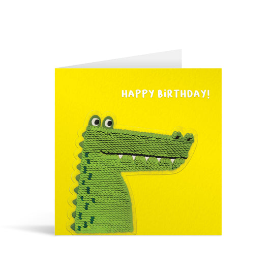 Yellow square greetings card with reversible sequin crocodile patch and fun, free-flowing text that reads "Happy Birthday!"