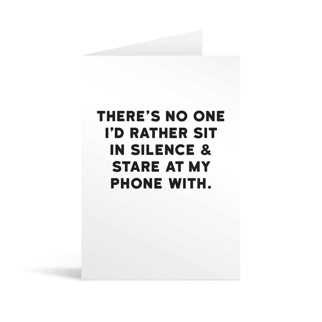 White rectangular card with black text saying: "There's no one I'd rather sit in silence & stare at my phone with."