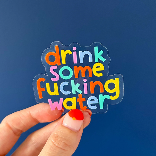 Transparent gloss vinyl sticker with multicoloured letters saying "Drink some fucking water" on a navy blue background