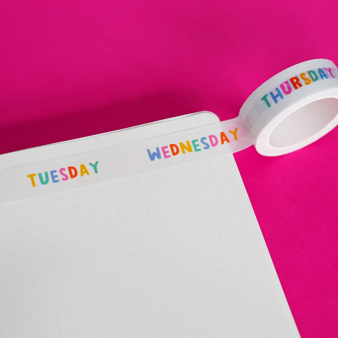 Wahi tape with the colourful lettering spelling out the days of the week, Tuesday, Wednesday and Thursday, stuck to a page in an open notebook.