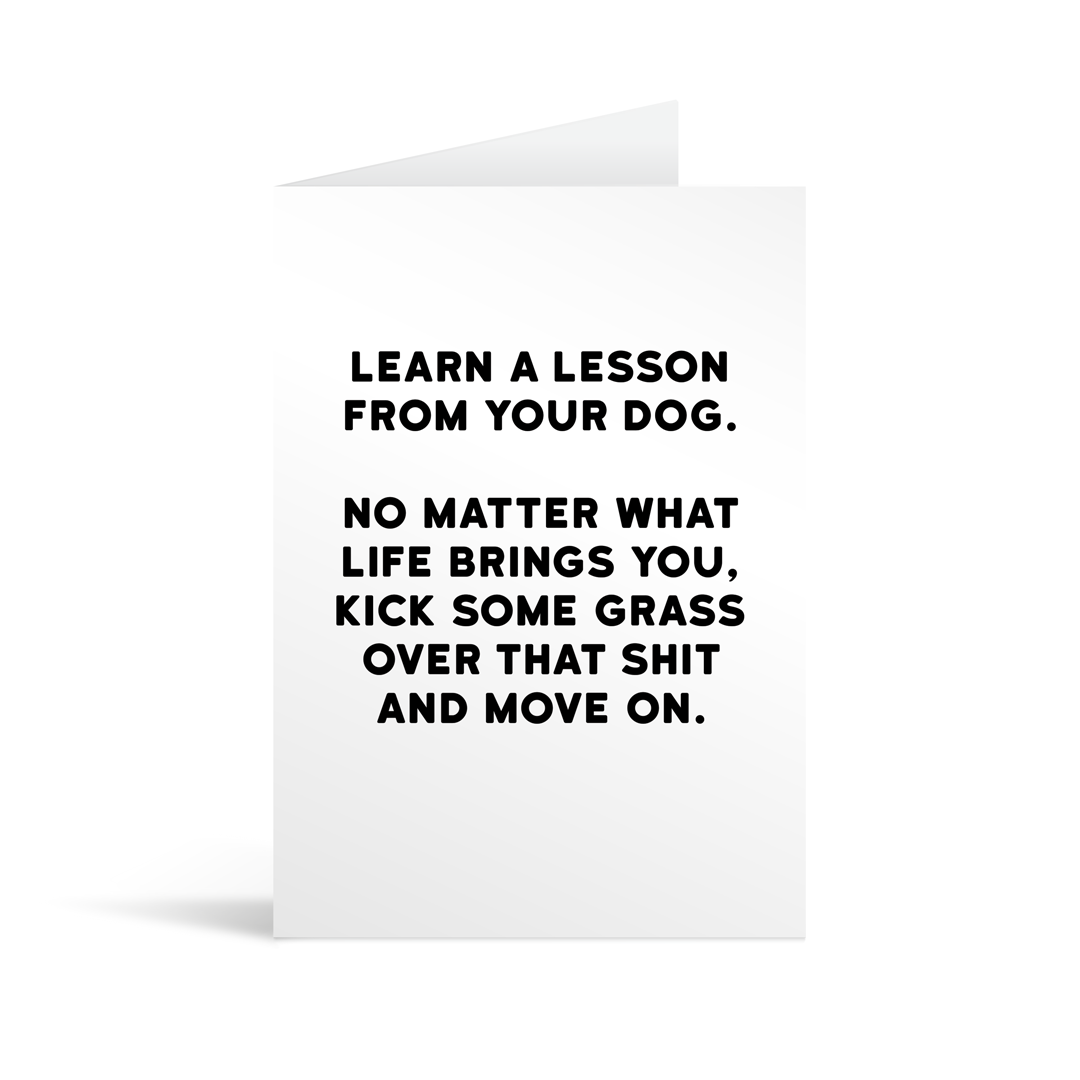 White rectangular card with black bold text reading "Learn a lesson from your dog. No matter what life brings you, kick some grass over that shit and move on." Neon orange envelope in the background.